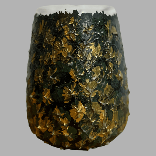 Nahaufnahme einer dekorativen Vase mit strukturierter Oberfläche. Die Vase ist mit einem Relief aus Blatt- und Blumenmotiven verziert, die in dunklen Grüntönen und goldenen Akzenten gehalten sind. Der obere Rand der Vase ist glatt und in einem hellen Farbton gehalten, während die Reliefstruktur die restliche Oberfläche bedeckt.